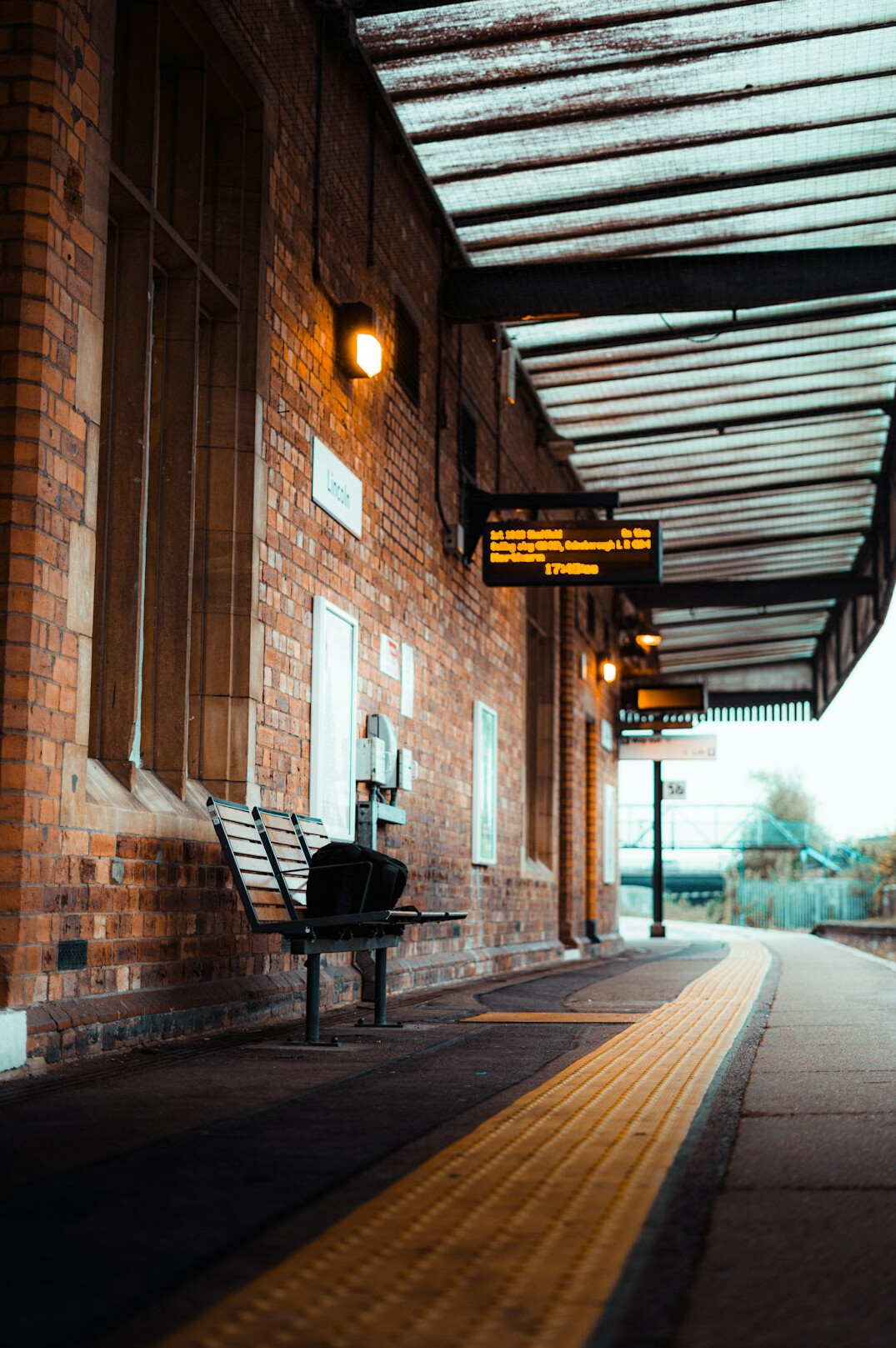Abandoned vintage railway station platform with rusted tracks and a wooden bench