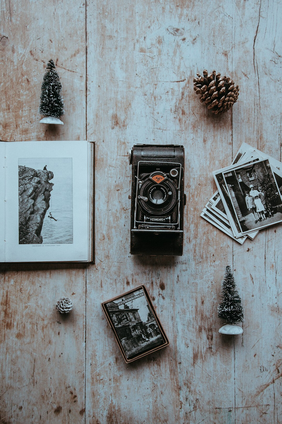 Top view of a wooden desk with old maps, vintage photographs and a magnifying glass